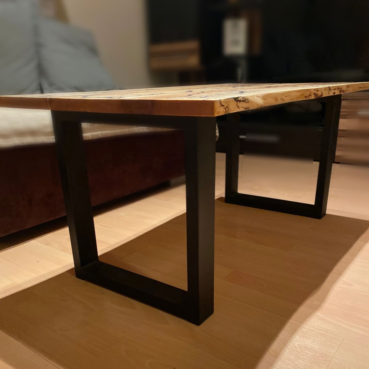 Seitenansicht mit blick auf den Couchtisch, der die einzigartige Mischung aus Lichtenberg-Figuren und grau-weißem und silbernem Epoxidharz zeigt