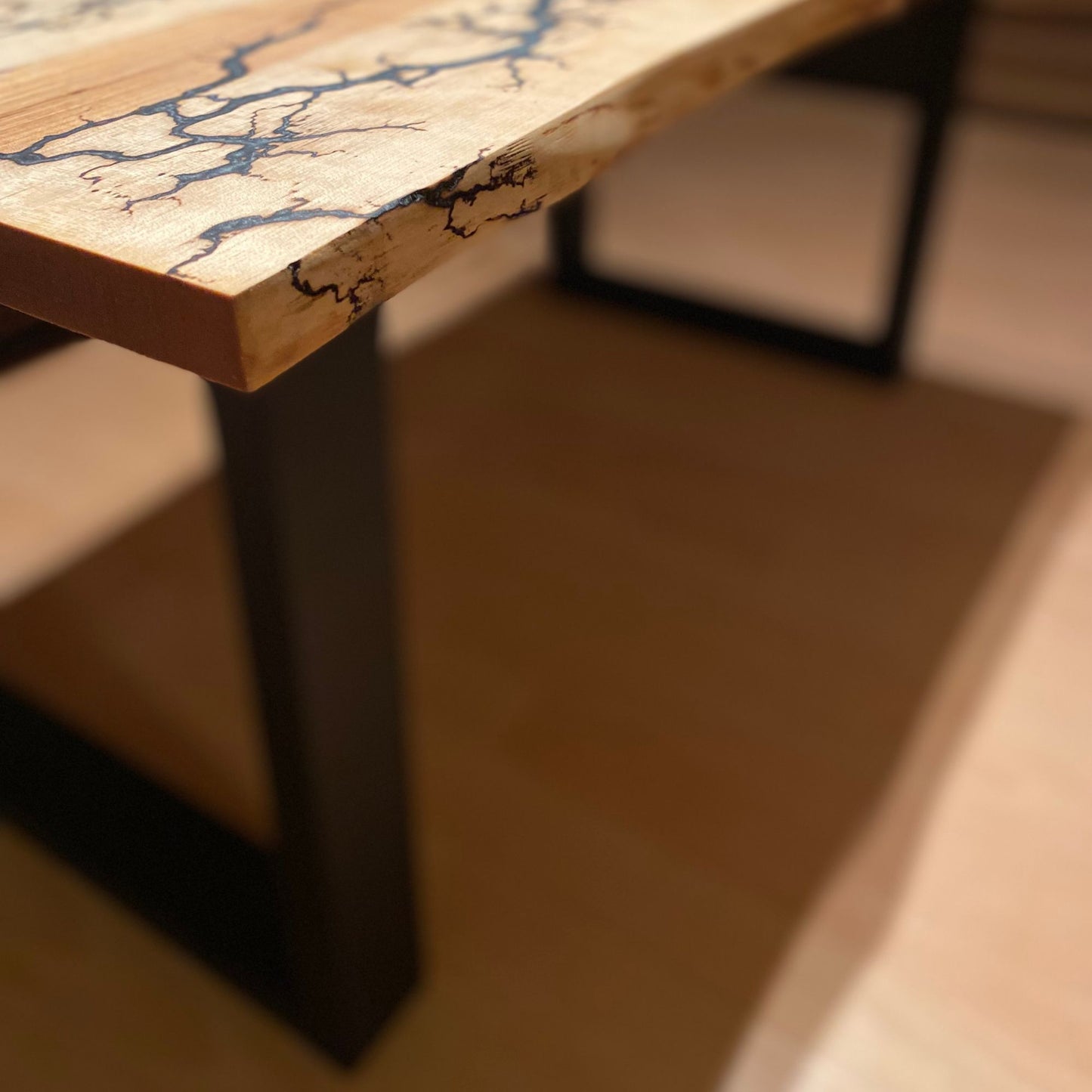 Couchtisch mit Baumkanten-Design, Lichtenberg-Figuren und grau-weißem und silbernem Epoxidharz auf schwarz pulverbeschichteten Stahlkufen.