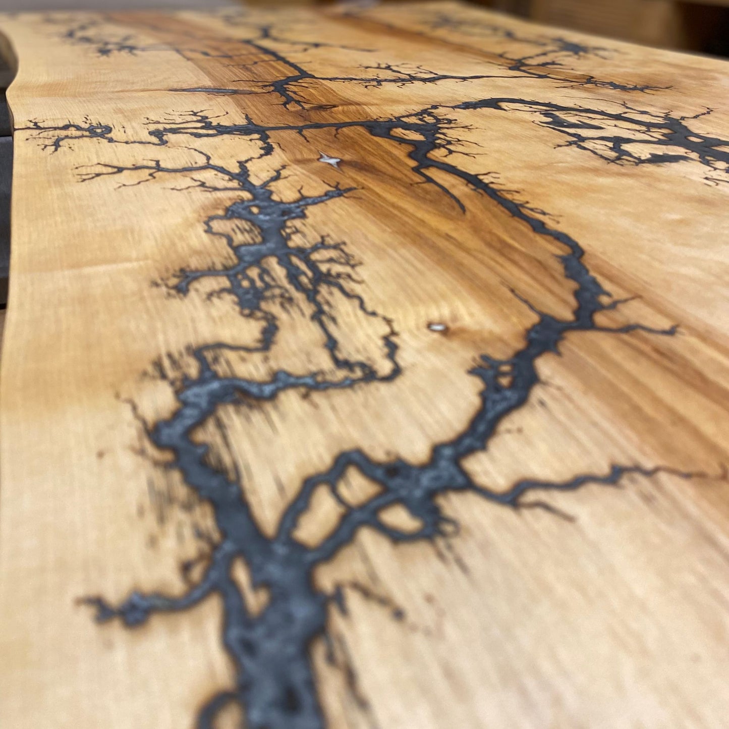 Nahaufnahme des Couchtisches, der die glatte Oberfläche und die detaillierten Lichtenberg-Figuren mit grau-weißem und silbernem Epoxidharz hervorhebt.
