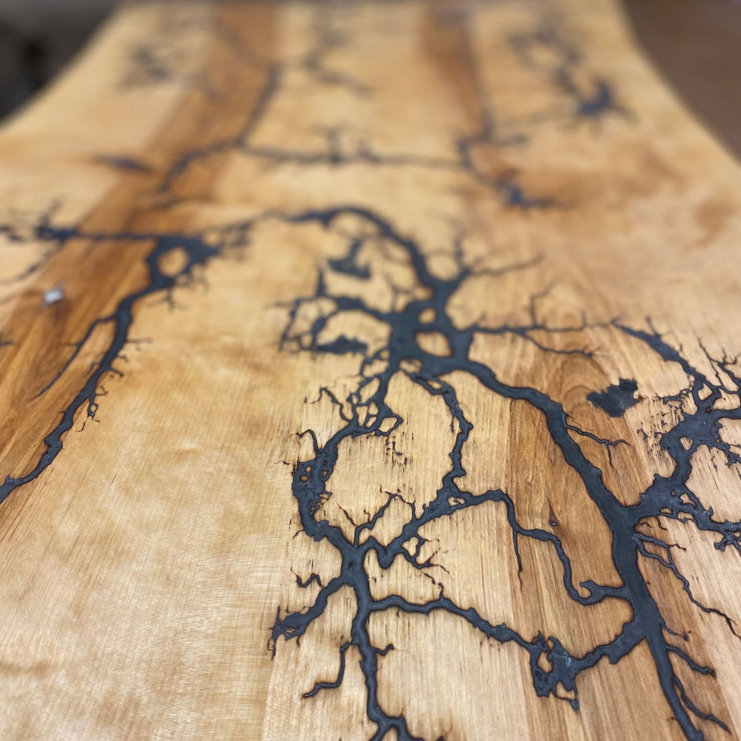 Couchtisch mit Baumkanten-Design, Lichtenberg-Figuren und grau-weißem und silbernem Epoxidharz auf schwarz pulverbeschichteten Stahlkufen.